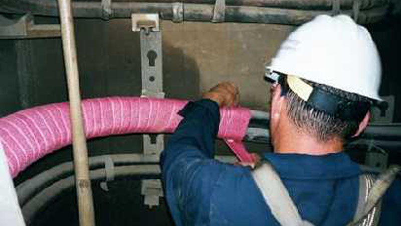 a man in a hardhat applying fire protection tape